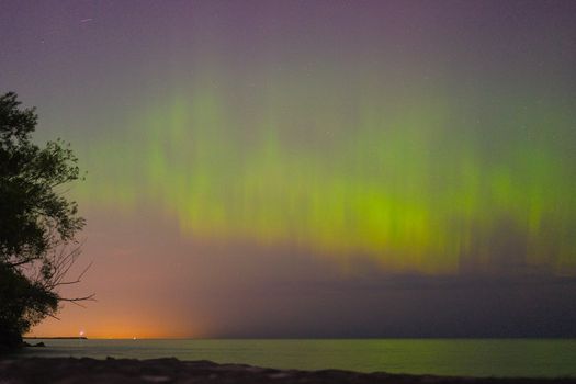 Vibrant Northern Lights dance over a tranquil lake landscape, creating a breathtaking view.