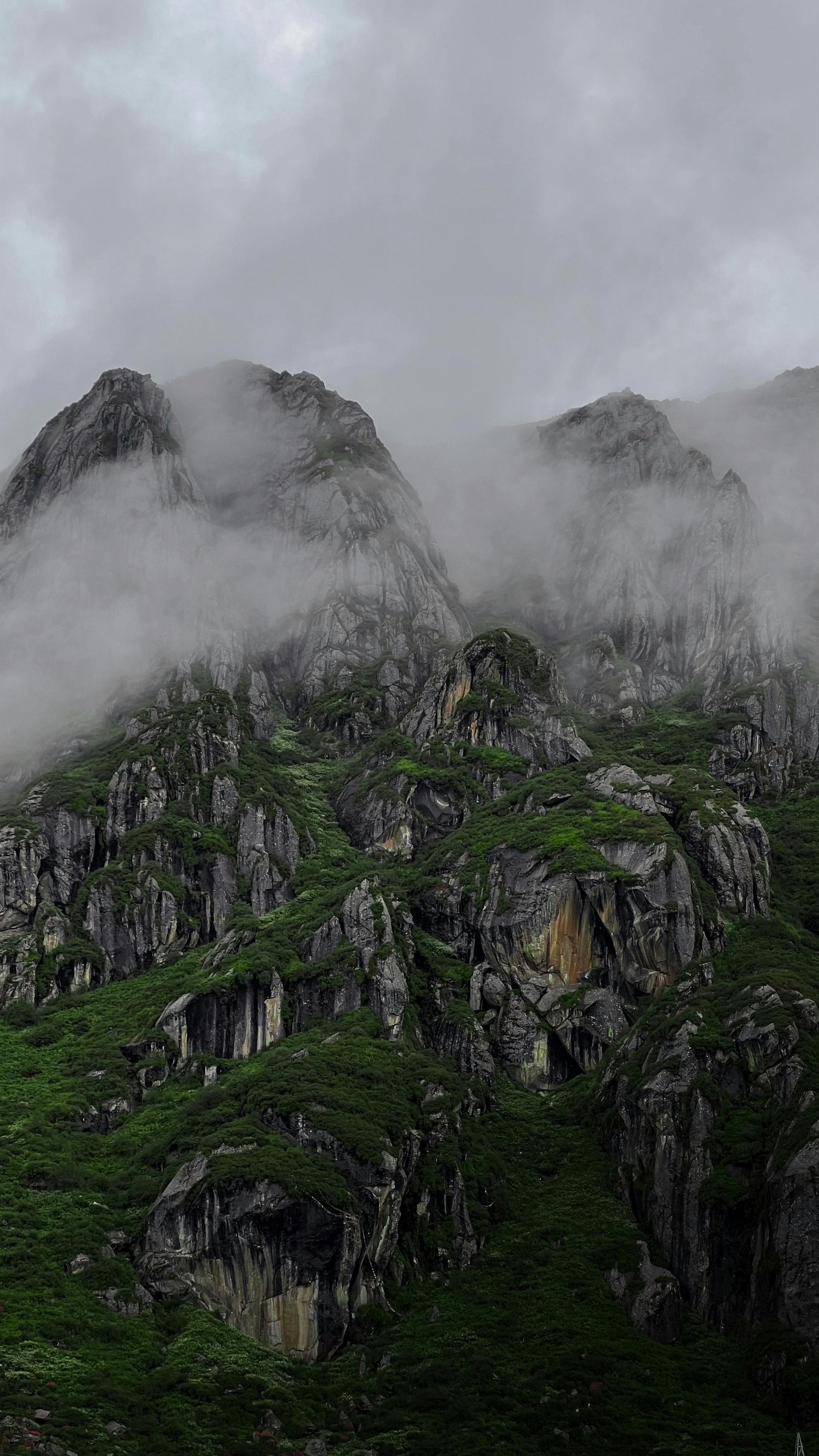 Captured in Gangtok, India, this misty mountain landscape features lush greenery and majestic rock formations.
