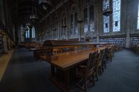 A spacious historic library with wooden tables and stained glass windows.