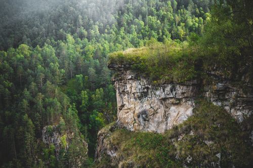Free A stunning cliff edge with lush green forest in the background, showcasing nature's beauty. Stock Photo