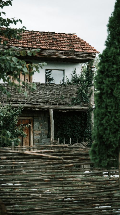 Free Charming rustic house with woven wooden fence and greenery. Stock Photo