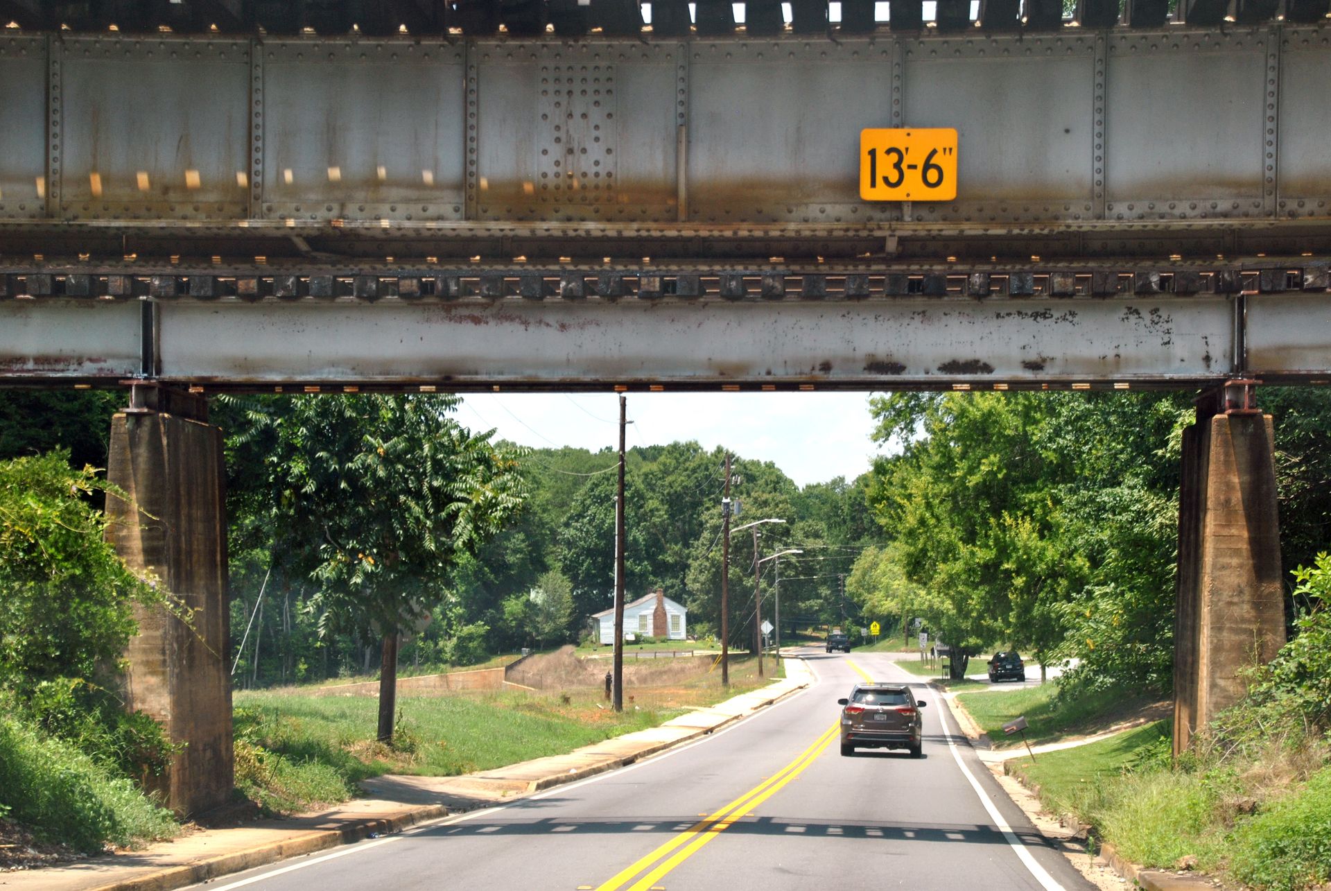 Country road under an overpass with a 13'6" height restriction sign.
