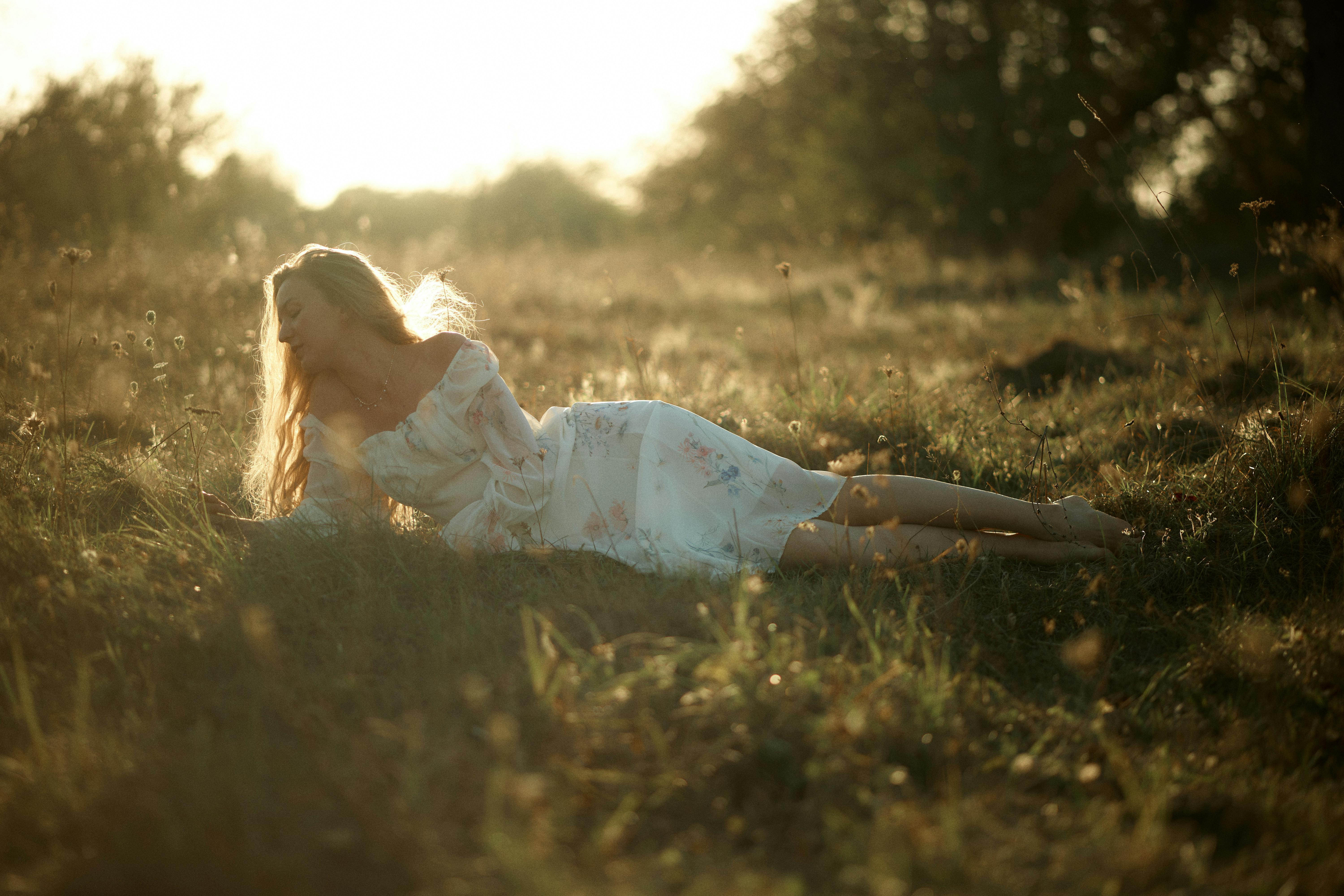 A woman in a floral dress enjoying a peaceful moment in a sunlit meadow.
