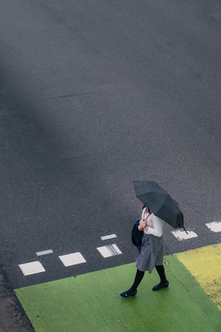Aerial view of a woman with an umbrella crossing a rainy street in Port Moody, Canada.