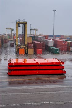 A port crane managing containers in a shipping yard during a rainy day.