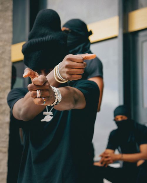 Free Group of masked adults in urban attire featuring jewelry, creating an edgy street style look. Stock Photo