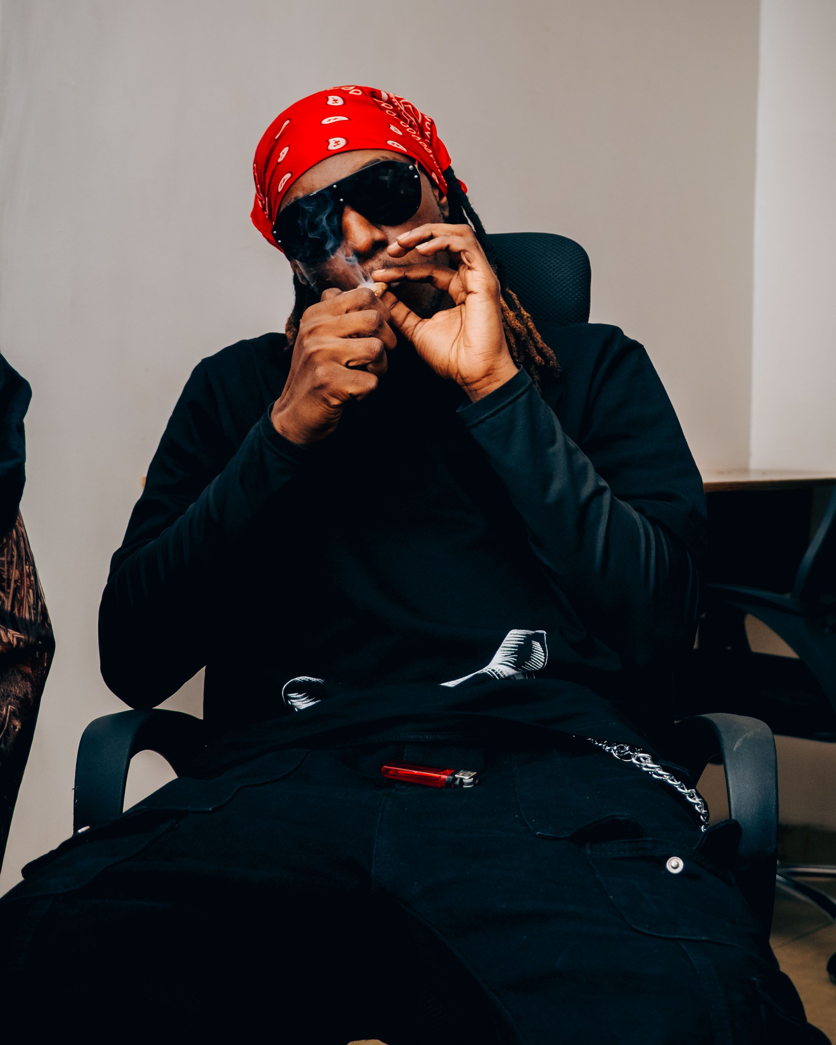 Man in casual wear seated with sunglasses and red bandana.