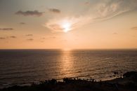 Golden sunset over Chapora, India, with the sun reflecting on the calm sea waters.