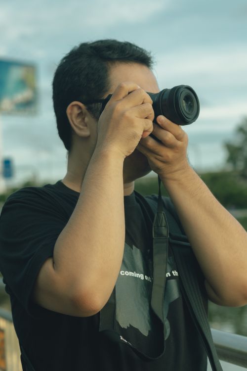 Free A street photographer in Ho Chi Minh City, Vietnam, capturing urban scenes with a camera. Stock Photo