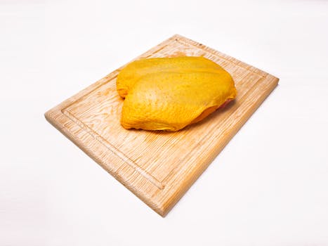 Uncooked chicken breast placed on a wooden cutting board, perfect for culinary needs.