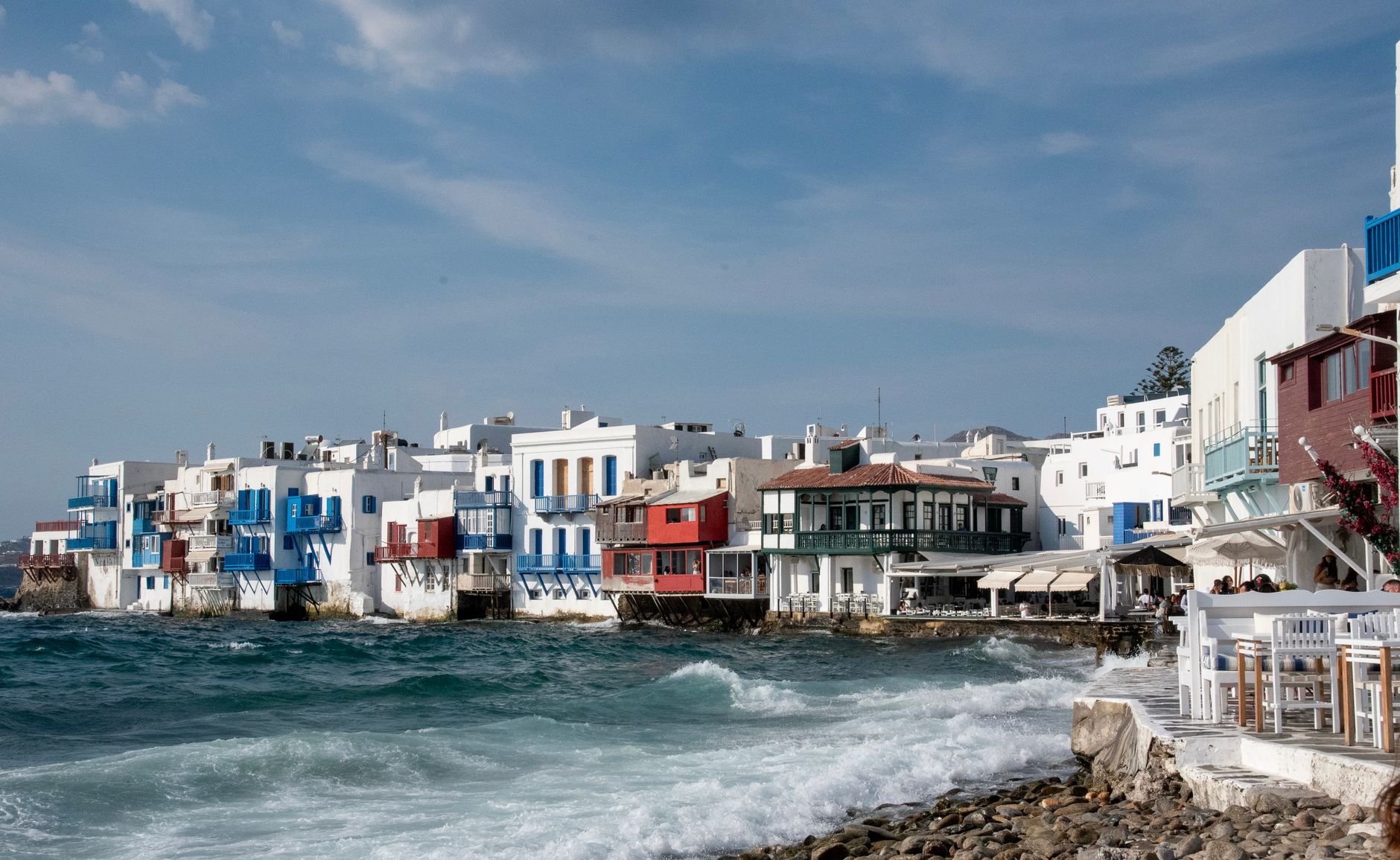 Charming coastal houses of Little Venice in Mykonos, Greece with vibrant colors and ocean waves.