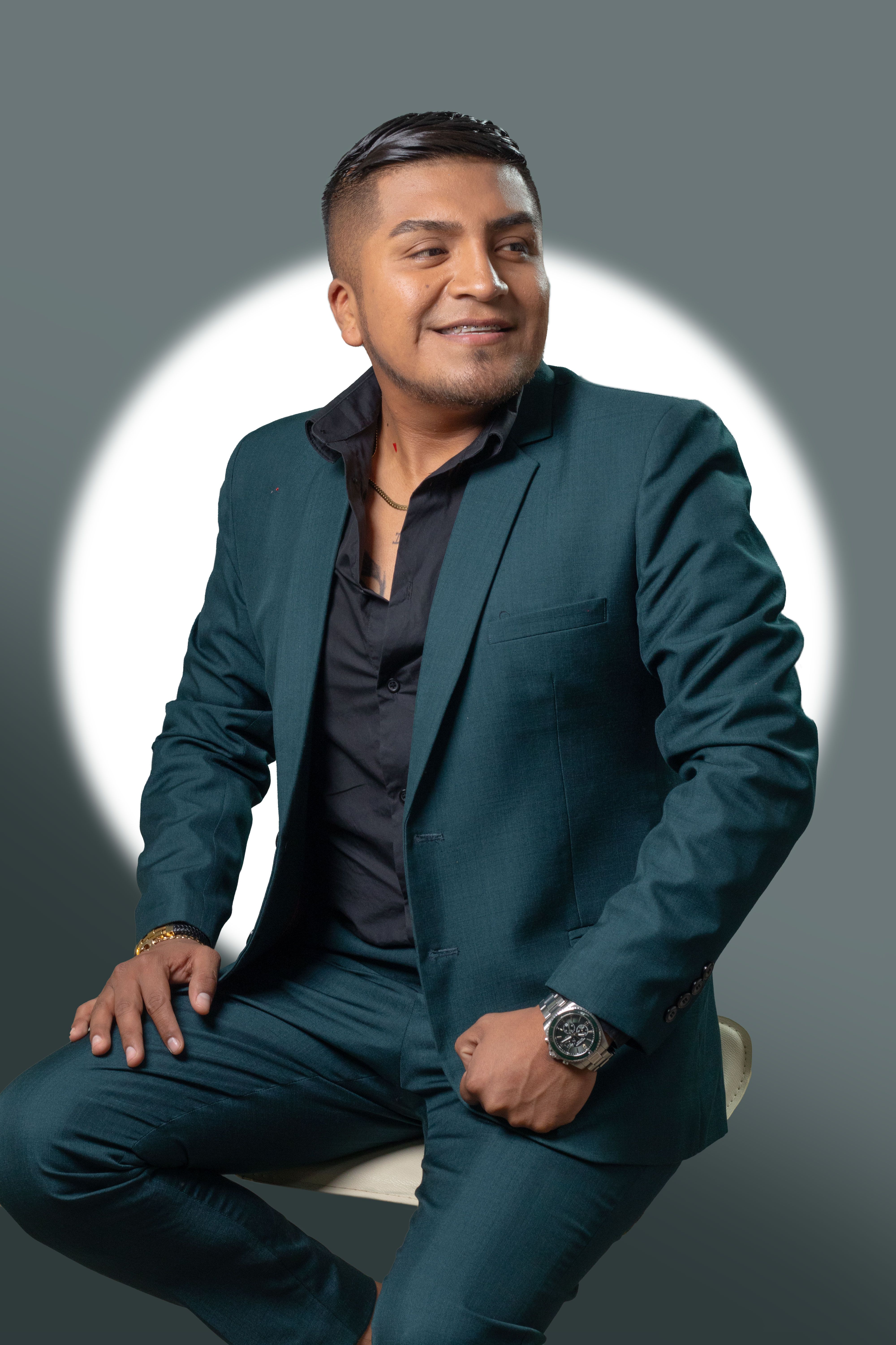 Portrait of a smiling man in a teal suit against a clean background, exuding confidence and style.