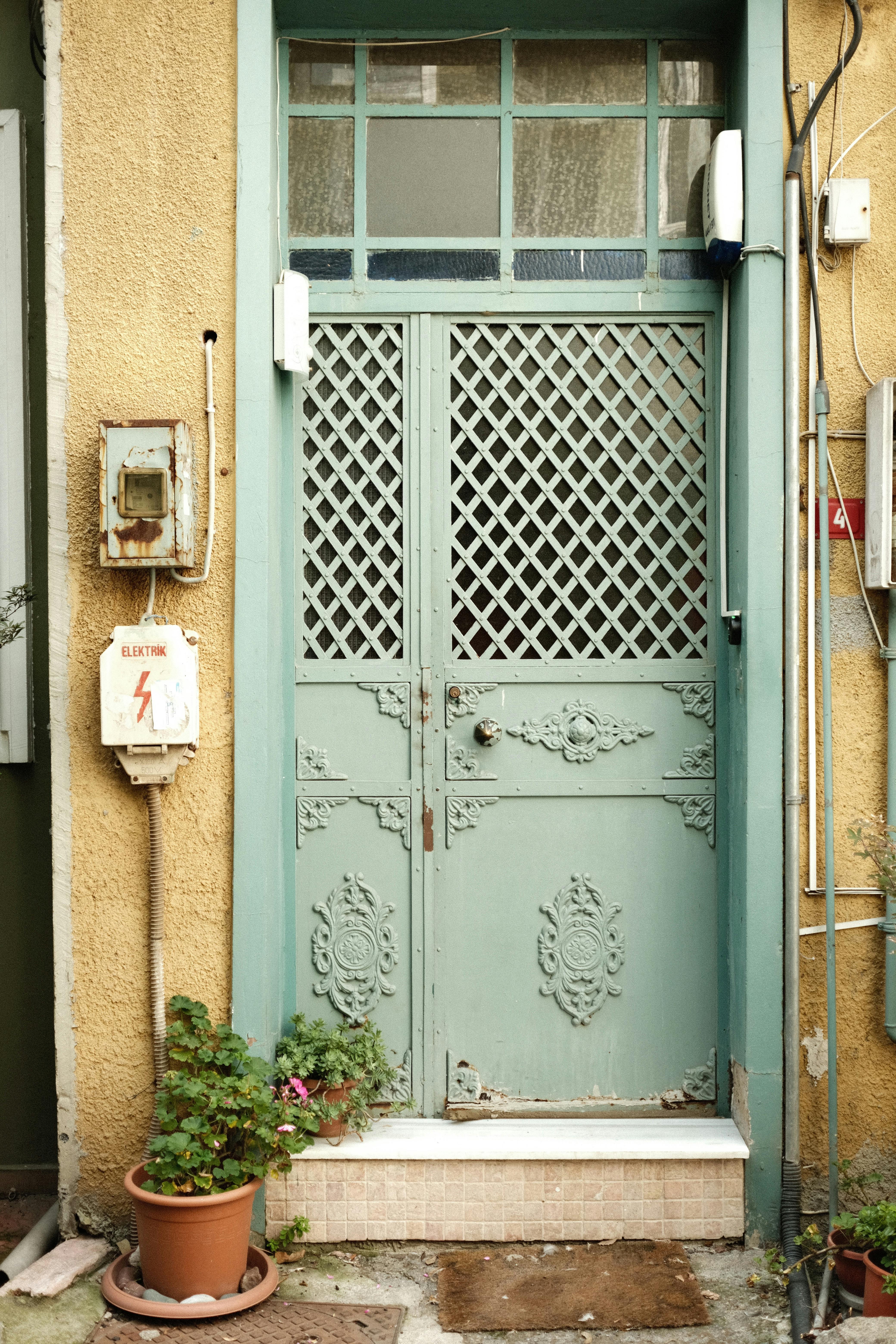 Charming turquoise door with intricate designs, set against a rustic exterior wall.