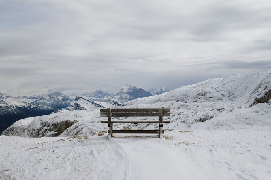 Empty bench overlooking snow-covered mountains in San Martino di Castrozza, Italy.