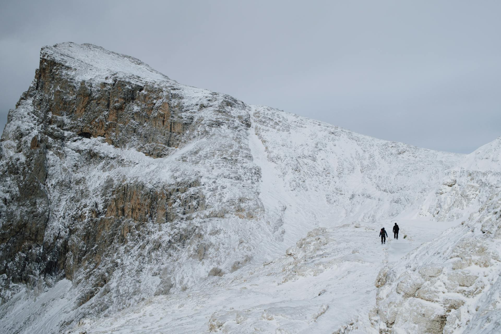 Two hikers on snowy mountains in San Martino di Castrozza, Italy.