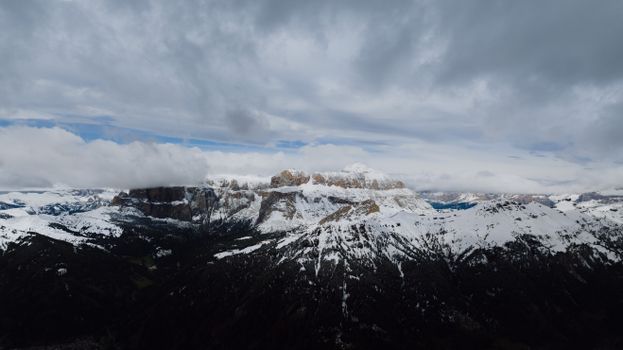 Breathtaking view of snow-capped mountains in Canazei, Italy under dramatic clouds.