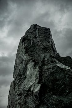 Moody rock formation against dark storm clouds, dramatic and intense.
