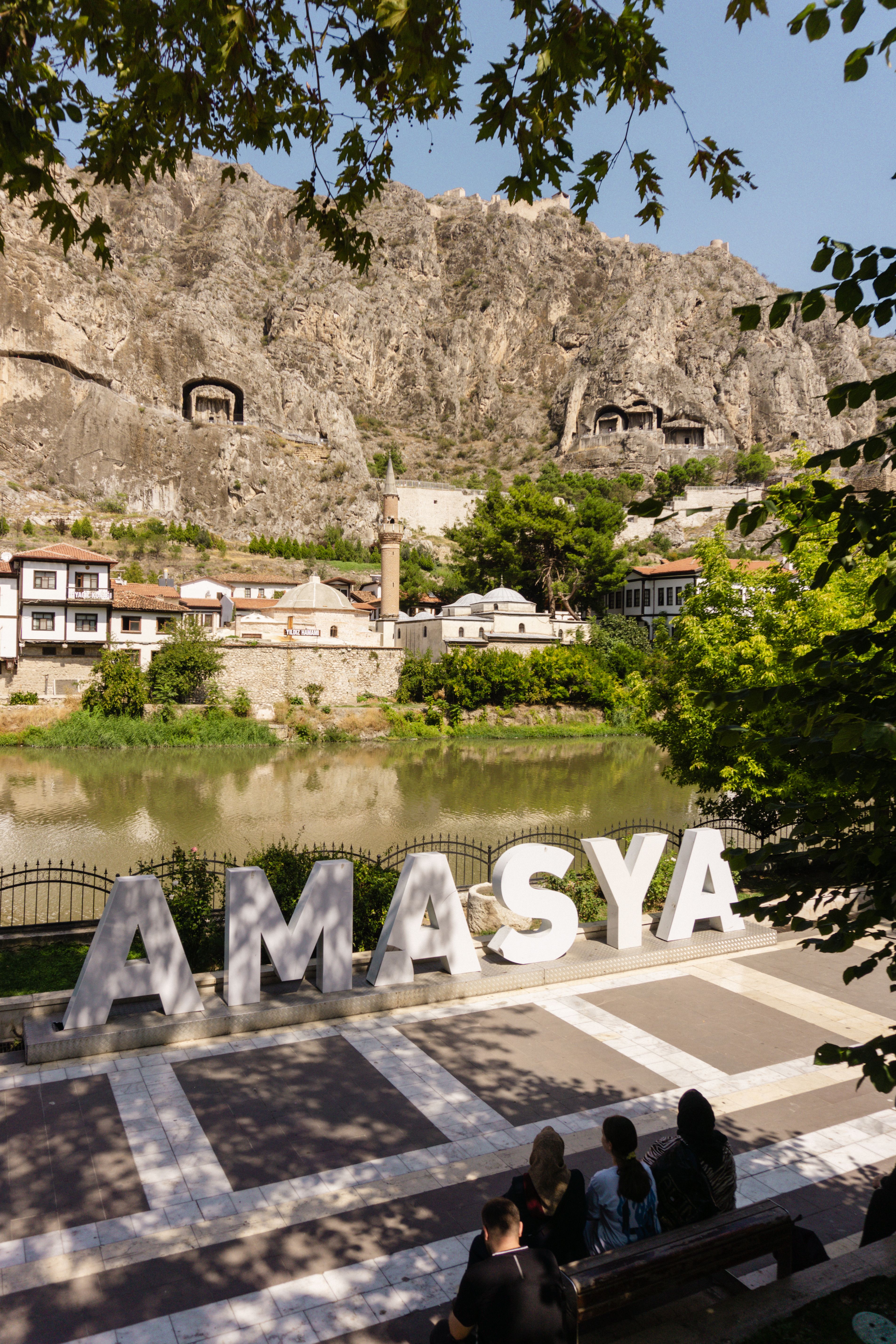 A scenic view of Amasya, Türkiye, showcasing iconic rock-cut tombs and riverside architecture.