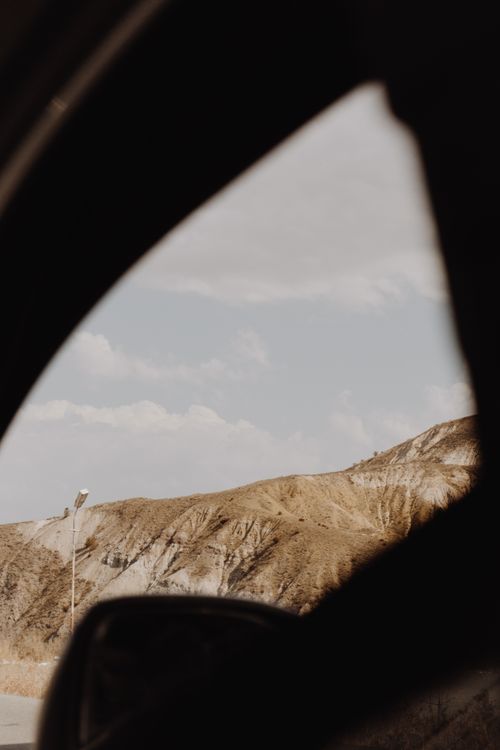 Free Brown desert hills viewed through car window, offering a serene natural scene. Stock Photo