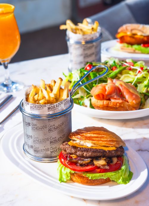 Free Delicious beef burger served with fries and fresh salad on a bright table setting. Stock Photo