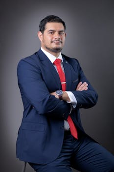 Professional portrait of a businessman in a suit with red tie, arms crossed.