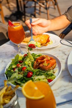 Vibrant outdoor dining scene with fresh salad, sandwich, and chilled drinks under sunny ambiance.