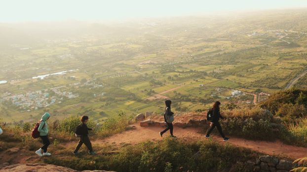 A group of hikers trekking a scenic mountain trail during sunrise with vast landscape views.
