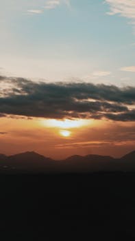 Stunning mountain silhouette during a vibrant sunset with dramatic clouds.