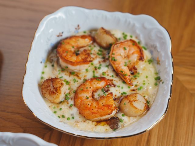Delicious creamy shrimp and scallops garnished with chives in a porcelain dish.