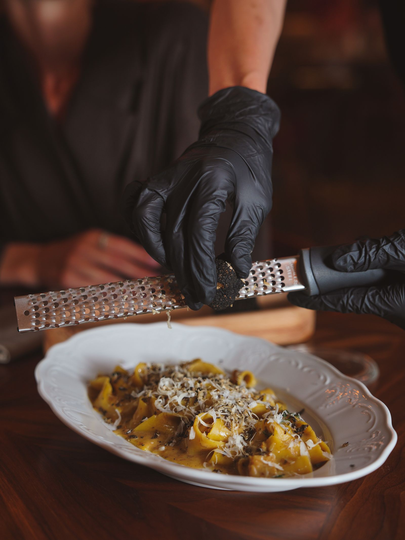 Tartufo nero grattugiato al tavolo sopra un piatto di pappardelle fresche