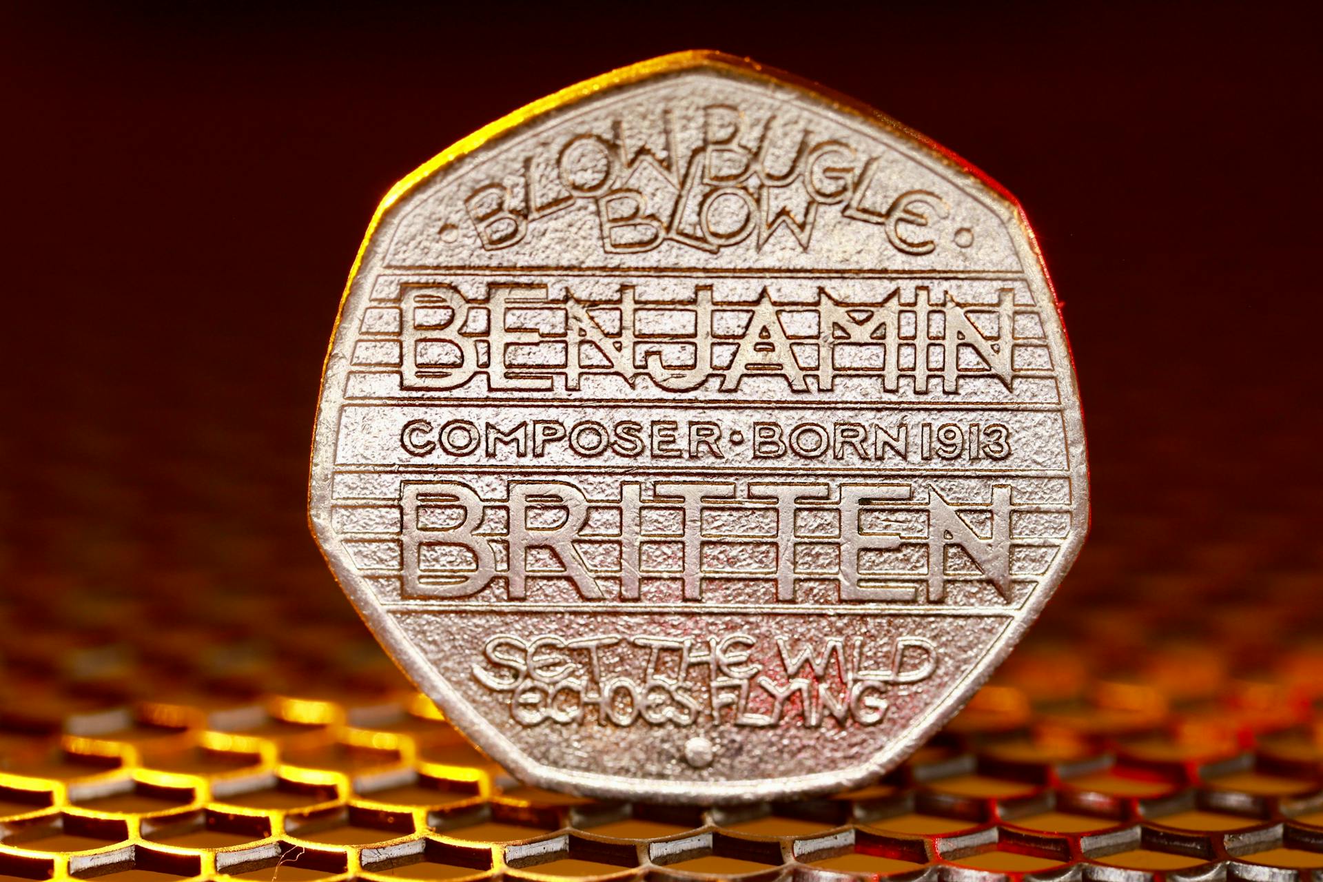 Magnified view of Benjamin Britten commemorative 50p coin with musical design.