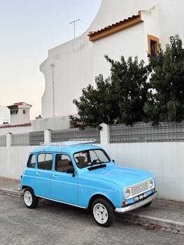 A vintage blue car parked beside a white villa in Faro, Portugal, capturing a summer vibe.