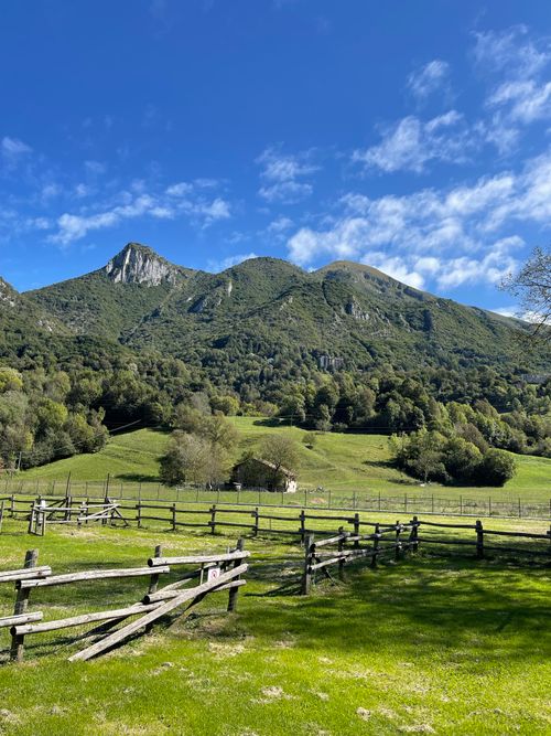 Free Green fields with a wooden fence and mountains under a bright blue sky. Stock Photo