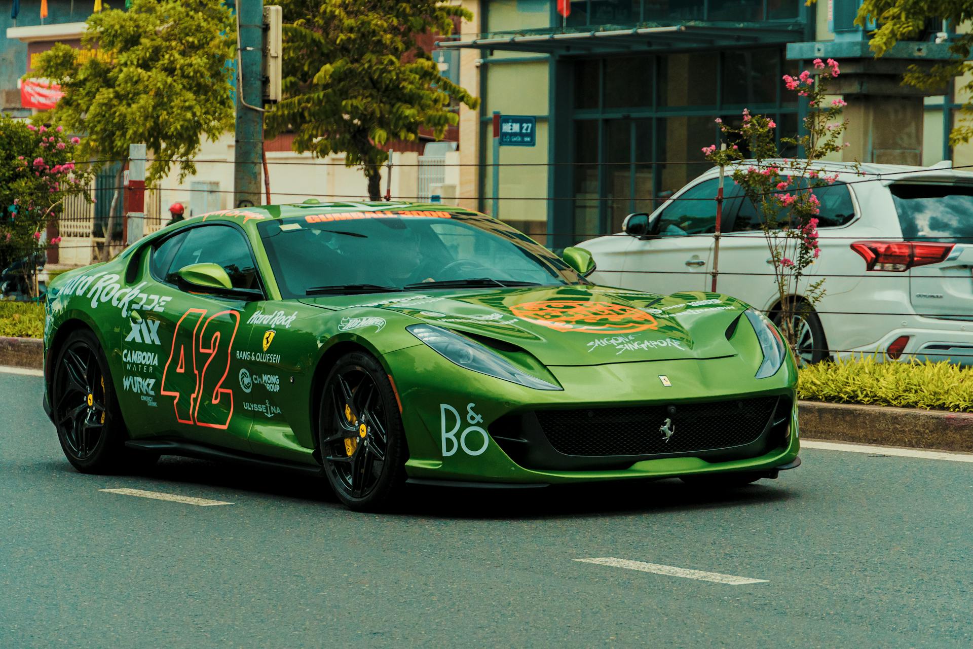 A vibrant green sports car with racing decals driving through a city street, showcasing speed.