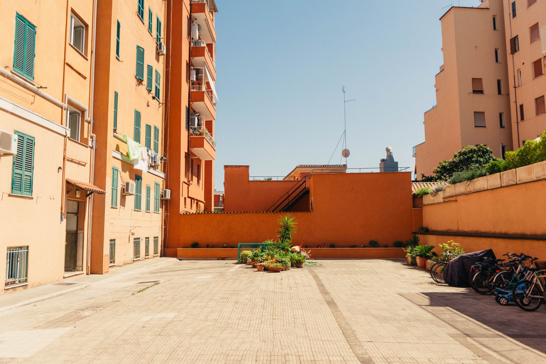 Sunlit courtyard of modern apartments in Rome, Italy, showcasing urban architecture.