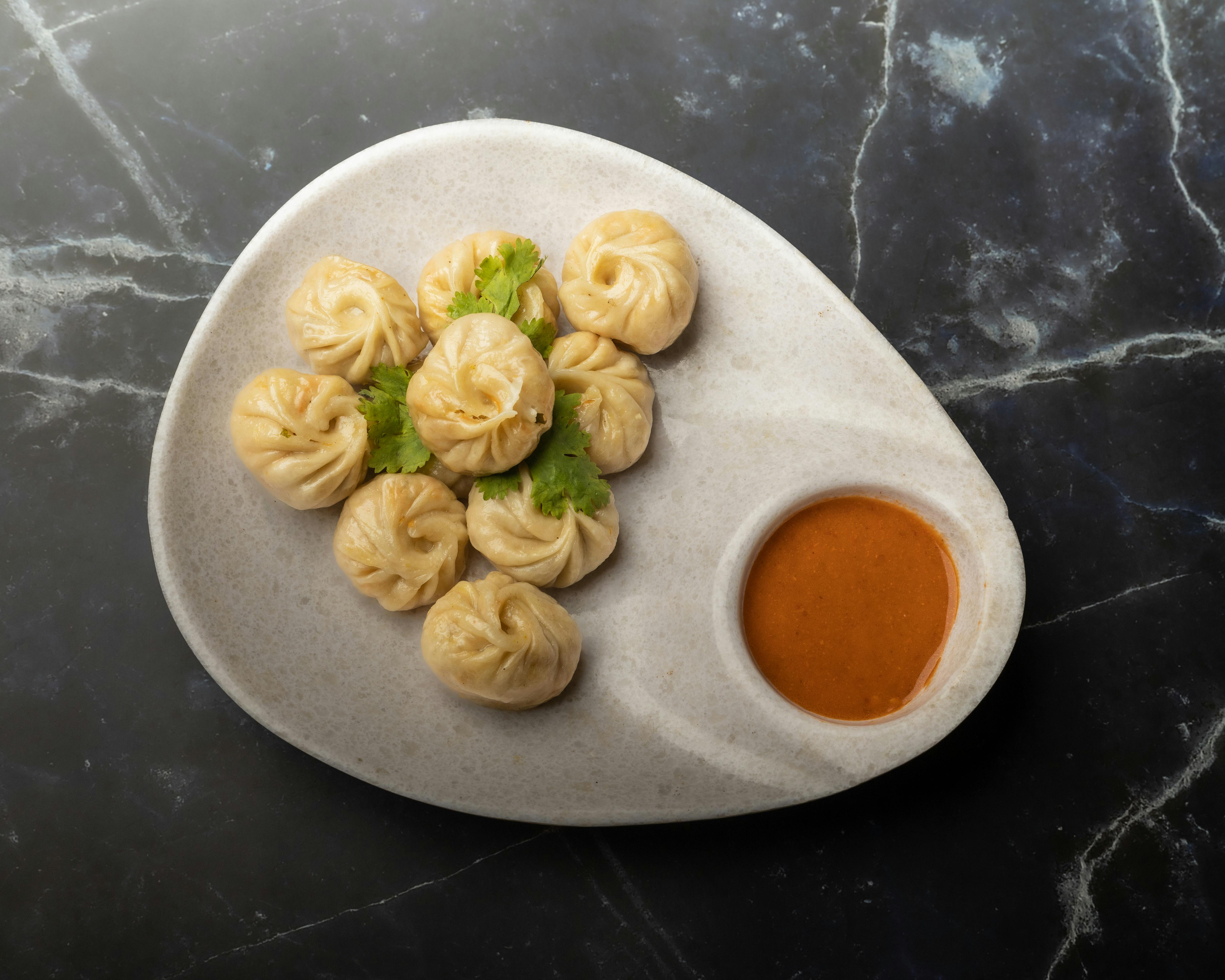 A plate of traditional Nepalese momos with spicy chutney. Perfect for food enthusiasts seeking authentic flavors.