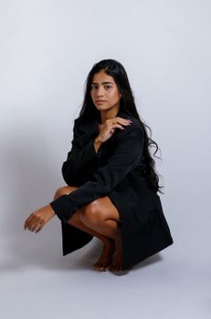 A stylish portrait of a woman in a black suit jacket against a neutral backdrop.