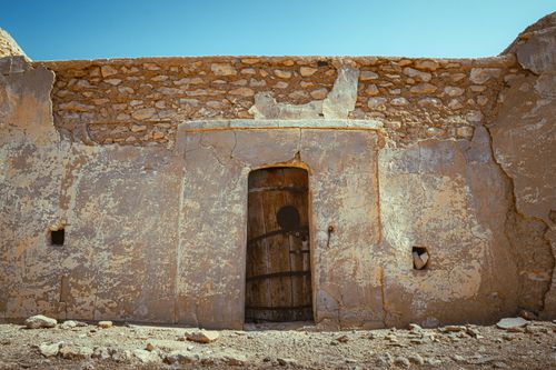 Free Ancient stone wall with a wooden door in Tataouine, Tunisia. Stock Photo
