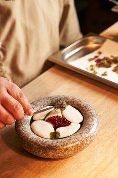 Close-up of a chef adding final touches to a gourmet dish with caviar in an elegant setting.