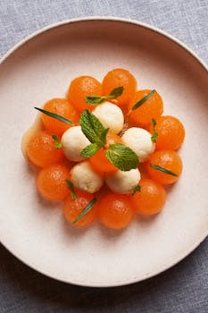 Top view of a decorative melon and cheese platter garnished with fresh mint.