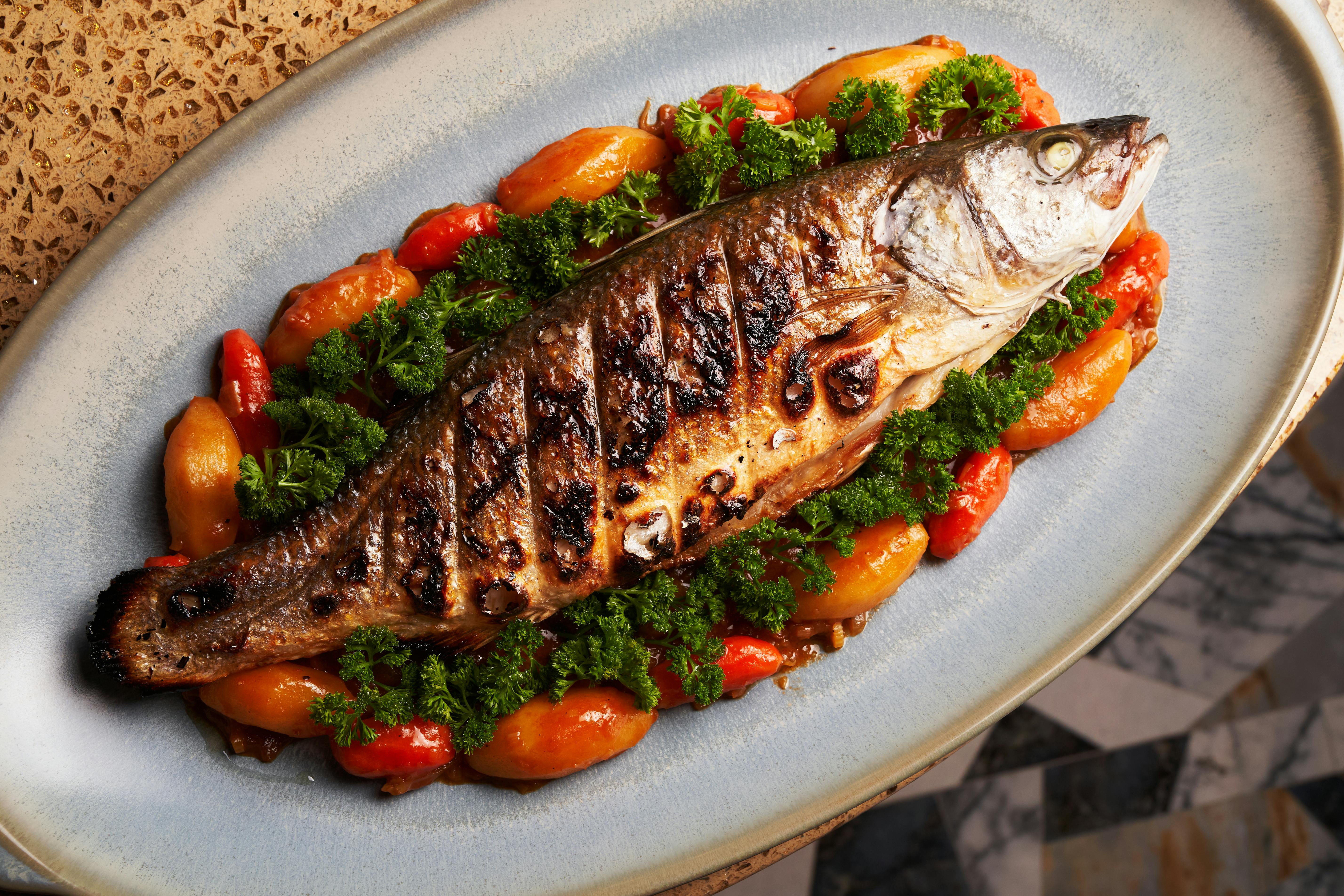 бесплатная Целая рыба на гриле с овощами на керамическом блюде Стоковое фото