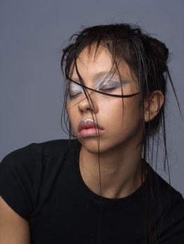 Expressive portrait of a woman with closed eyes and wet hair, revealing emotion.