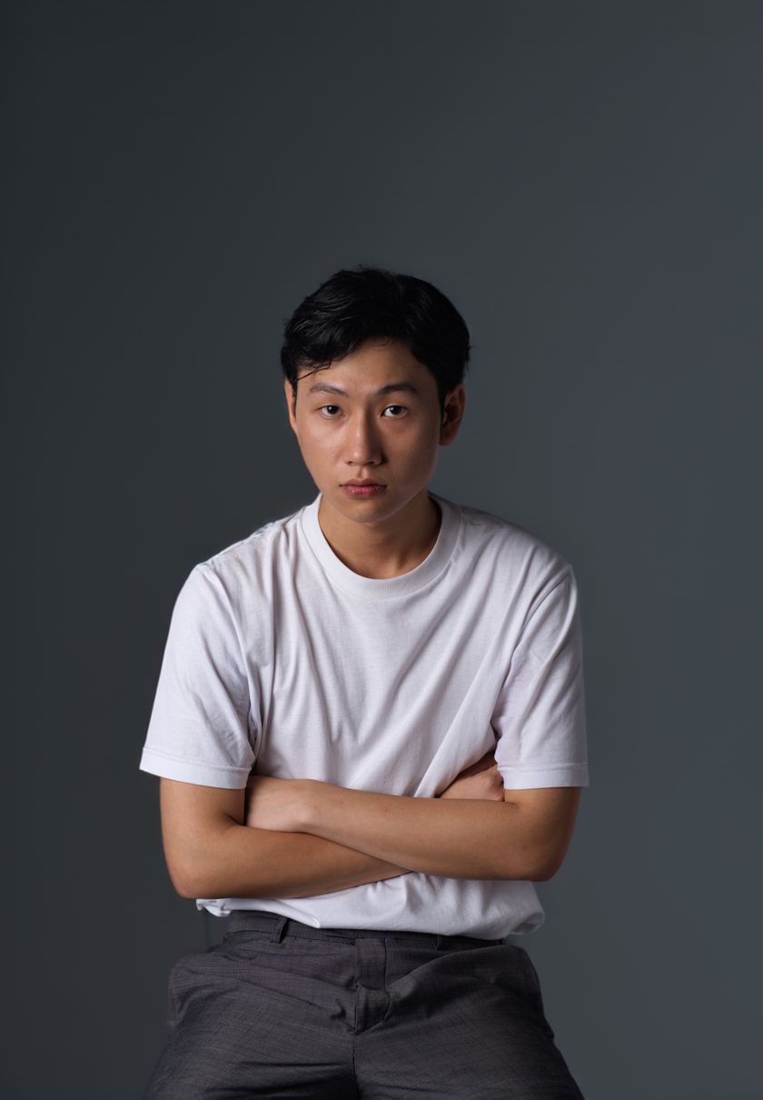 Young man in a plain white t-shirt against a charcoal studio backdrop — photo by Augusto Carneiro Junior on Pexels