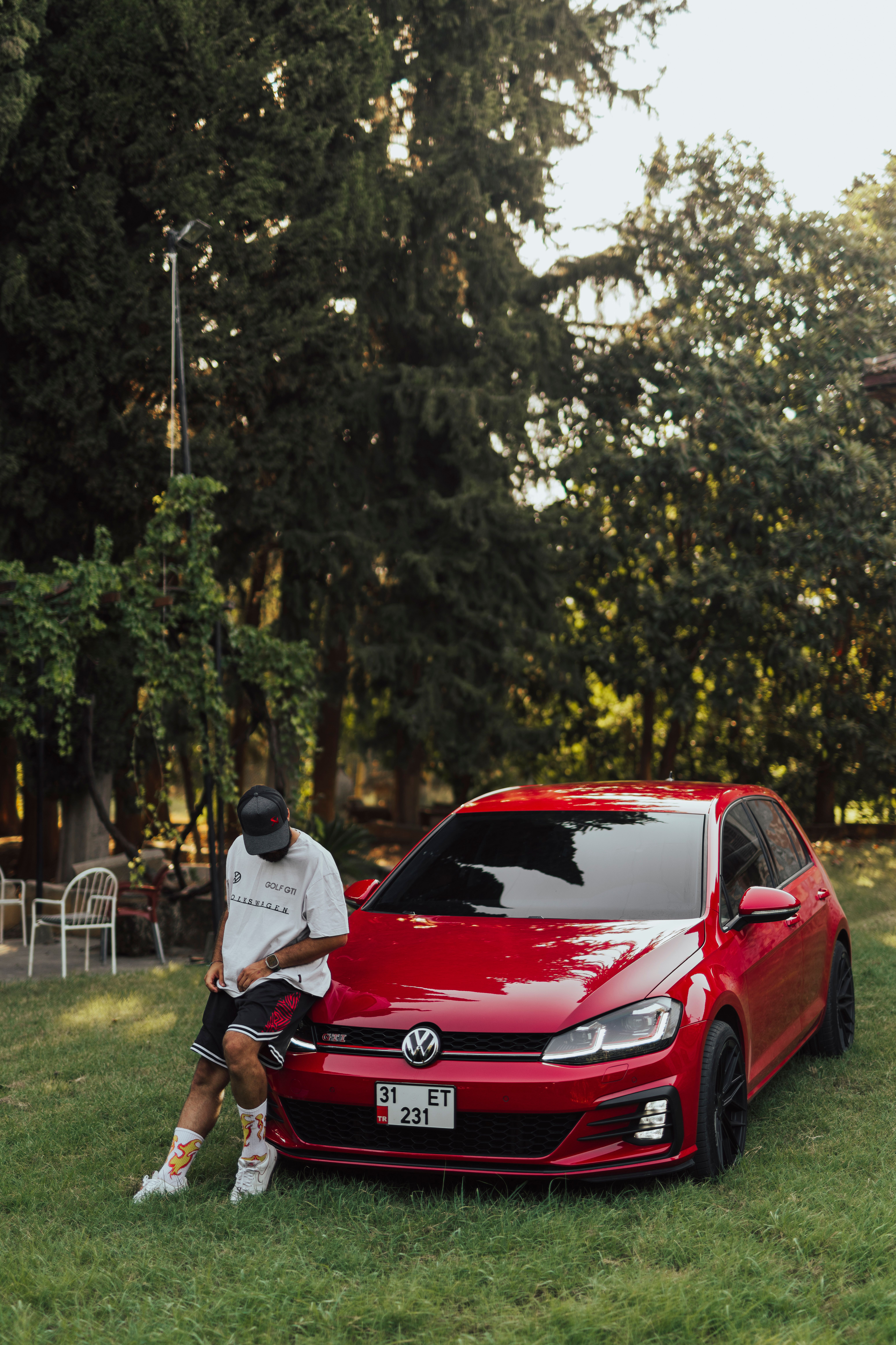 Outdoor shot of a red Volkswagen Golf GTI with a person nearby.