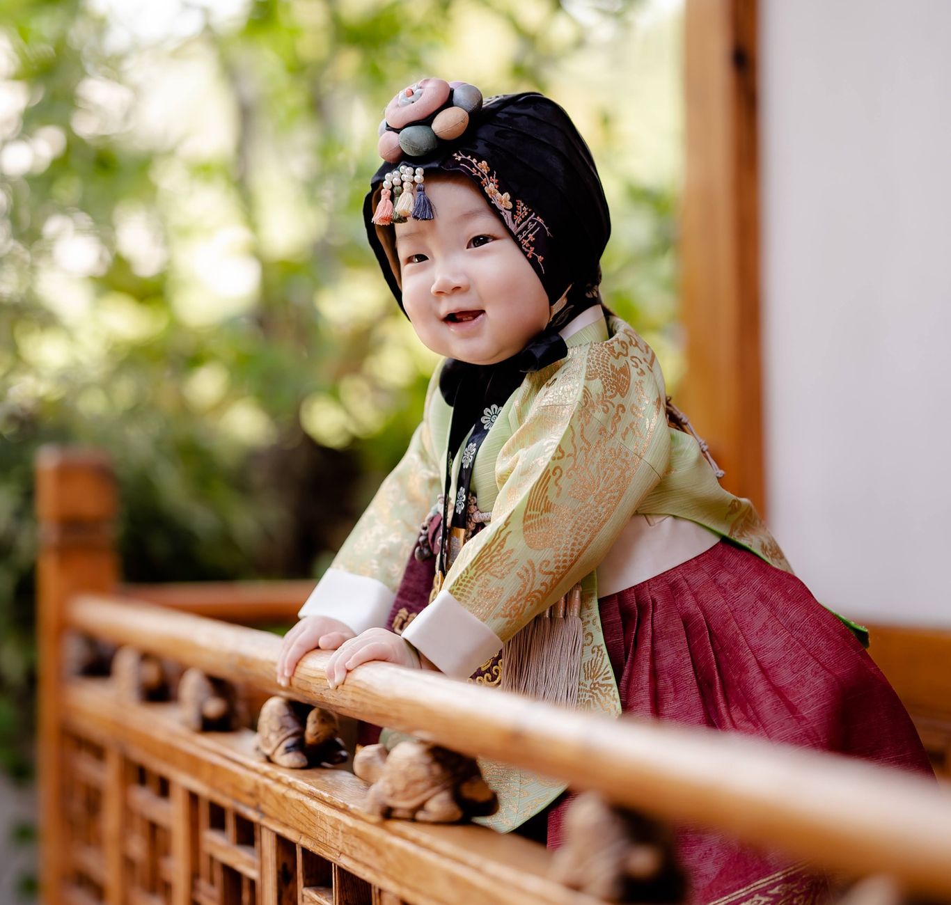 A joyful baby dressed in a colorful traditional Korean hanbok enjoying outdoor play.