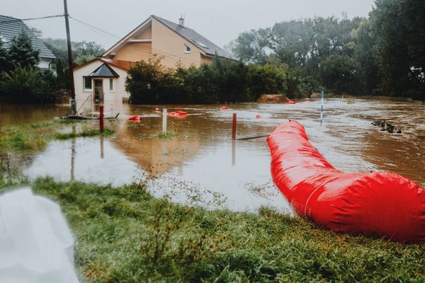 House surrounded by floodwater with a flood barrier