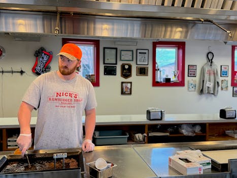 A chef at work in Nick's Hamburger Shop, Brookings, SD, preparing delicious hamburgers.