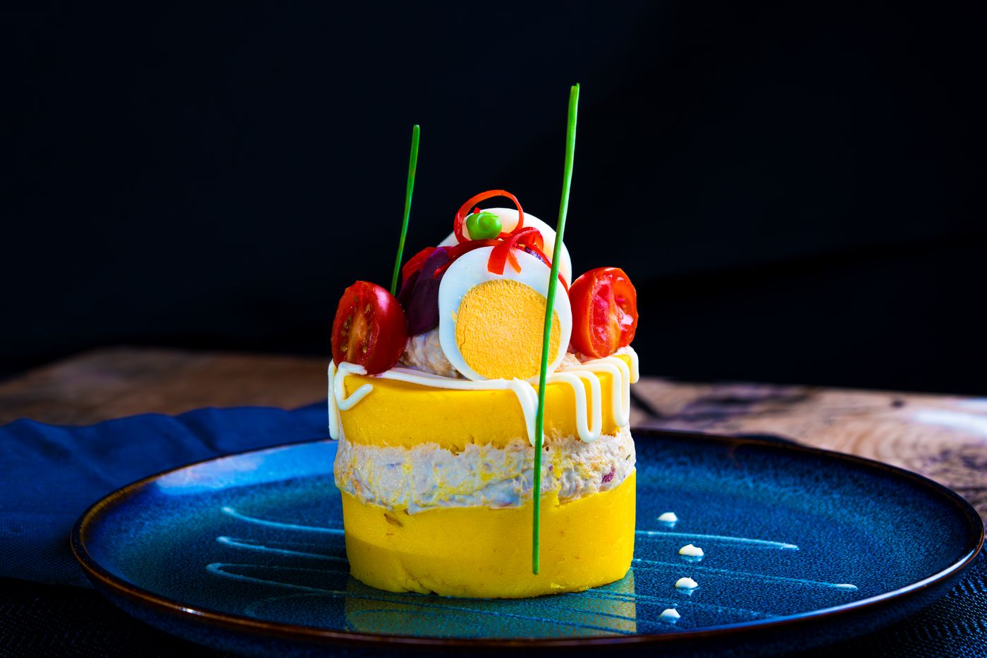 Vibrant Peruvian Causa Rellena with artistic presentation on a blue plate.