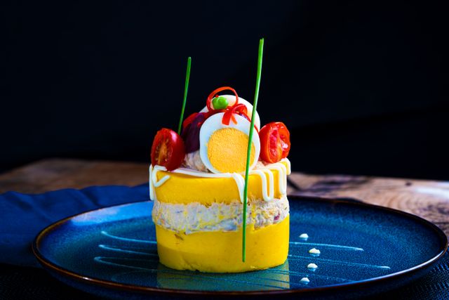 Vibrant Peruvian Causa Rellena with artistic presentation on a blue plate.