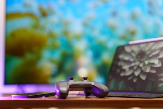 A modern gaming setup featuring a controller, laptop, and vibrant TV screen in a cozy home environment.
